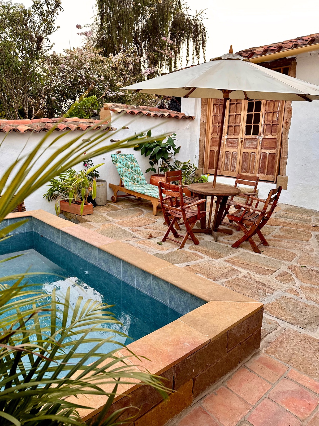 Patio con piscina, piso en laja de piedra y parasol