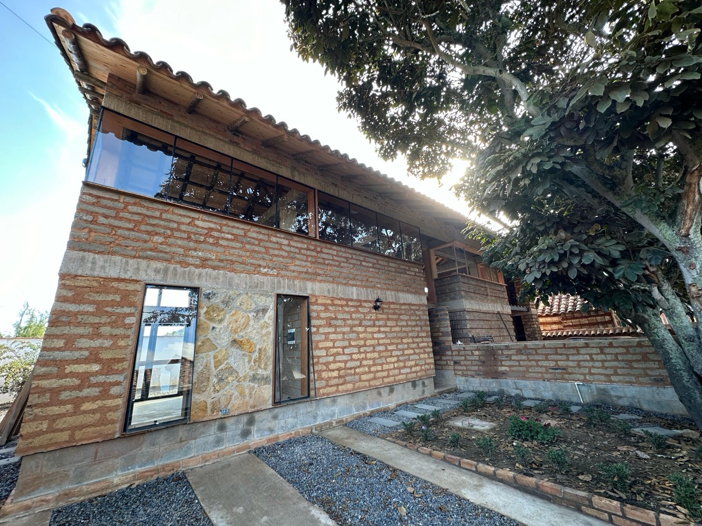 Casa de dos niveles en ladrillo a la vista con balcón en madera
