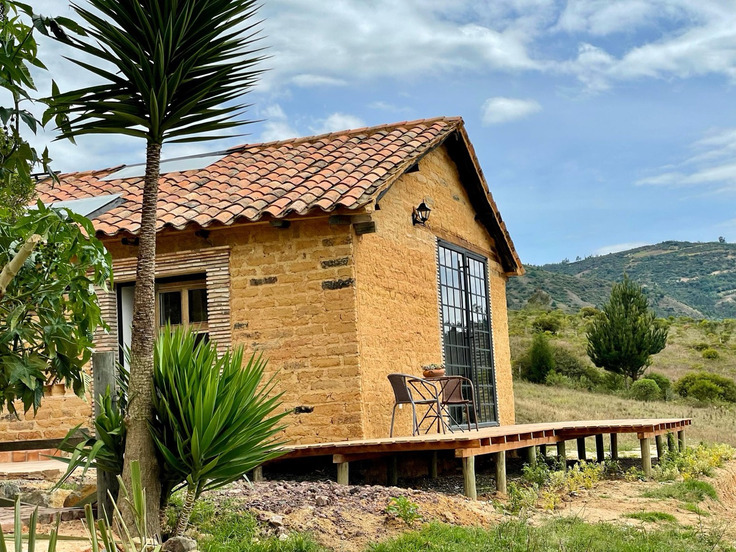 Casa en adobe con cubierta en teja de barro y deck en madera